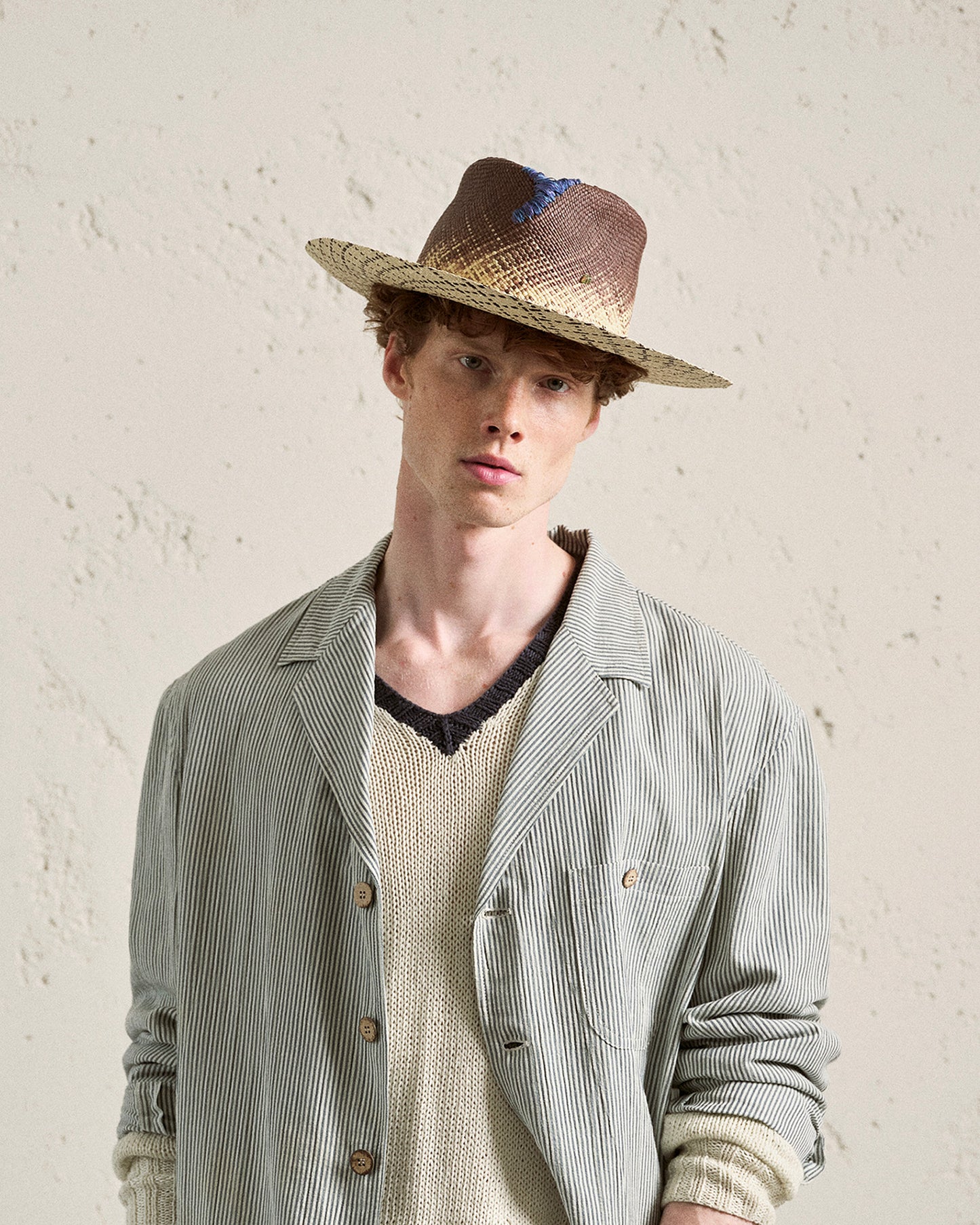 Man wearing a handmade Italian straw hat with blue detail and a striped blazer
