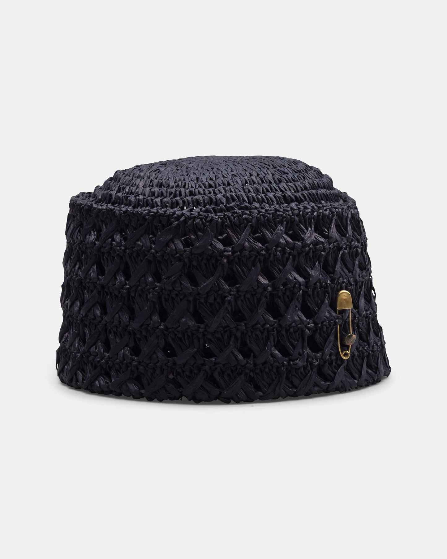 Handmade black woven straw hat with open pattern and gold safety pin detail on white background