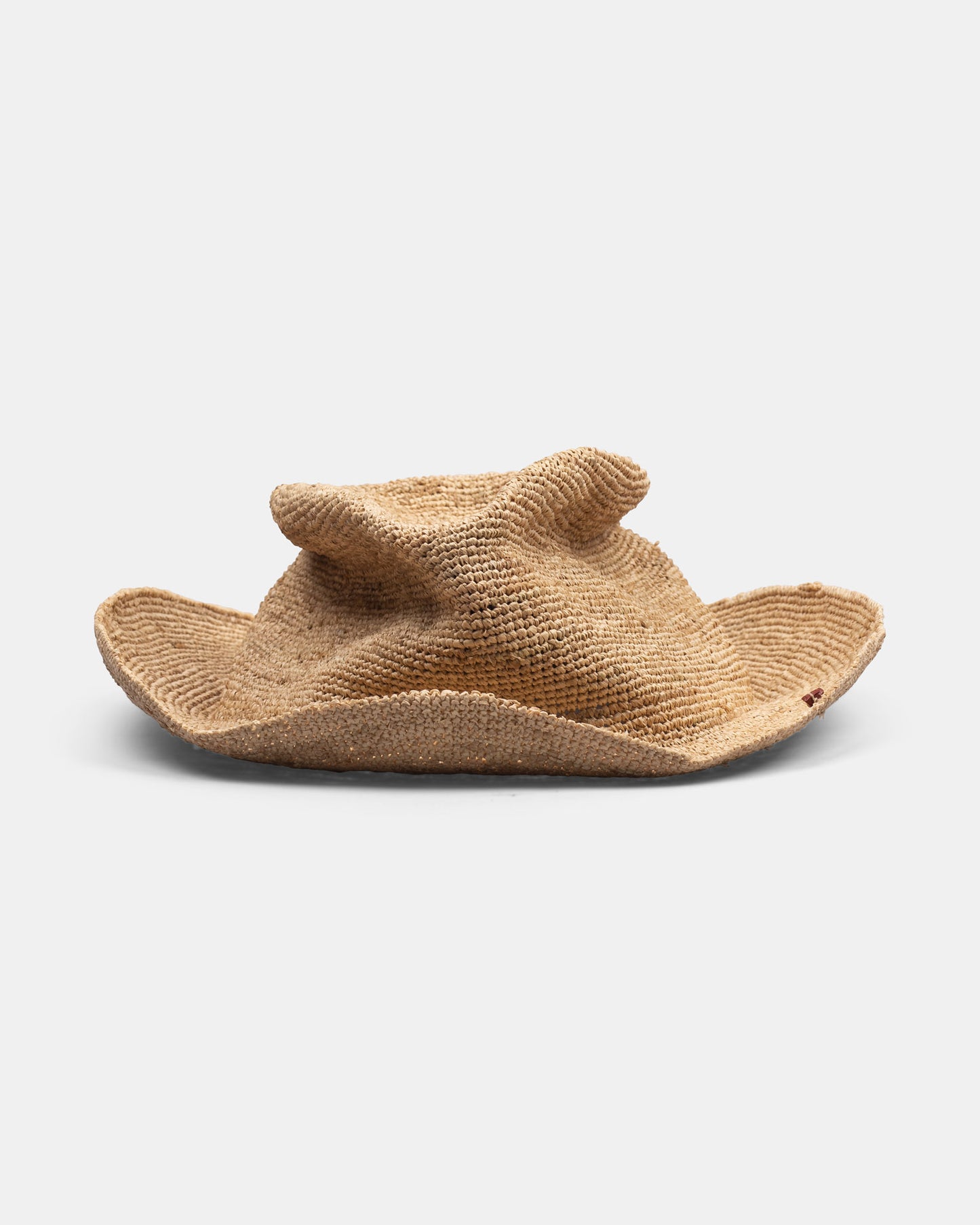 Handmade Italian straw hat with irregular wide brim on white background