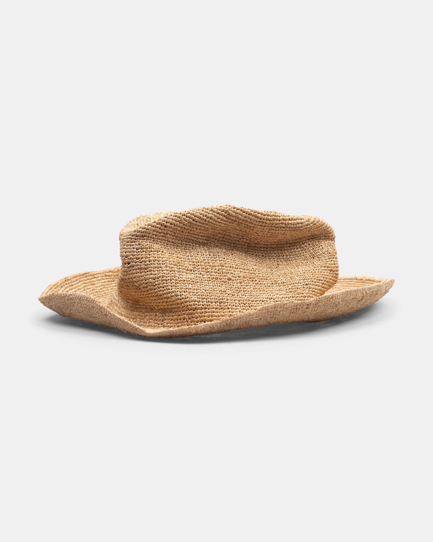 Handmade natural straw hat with wide, floppy brim on plain white background.