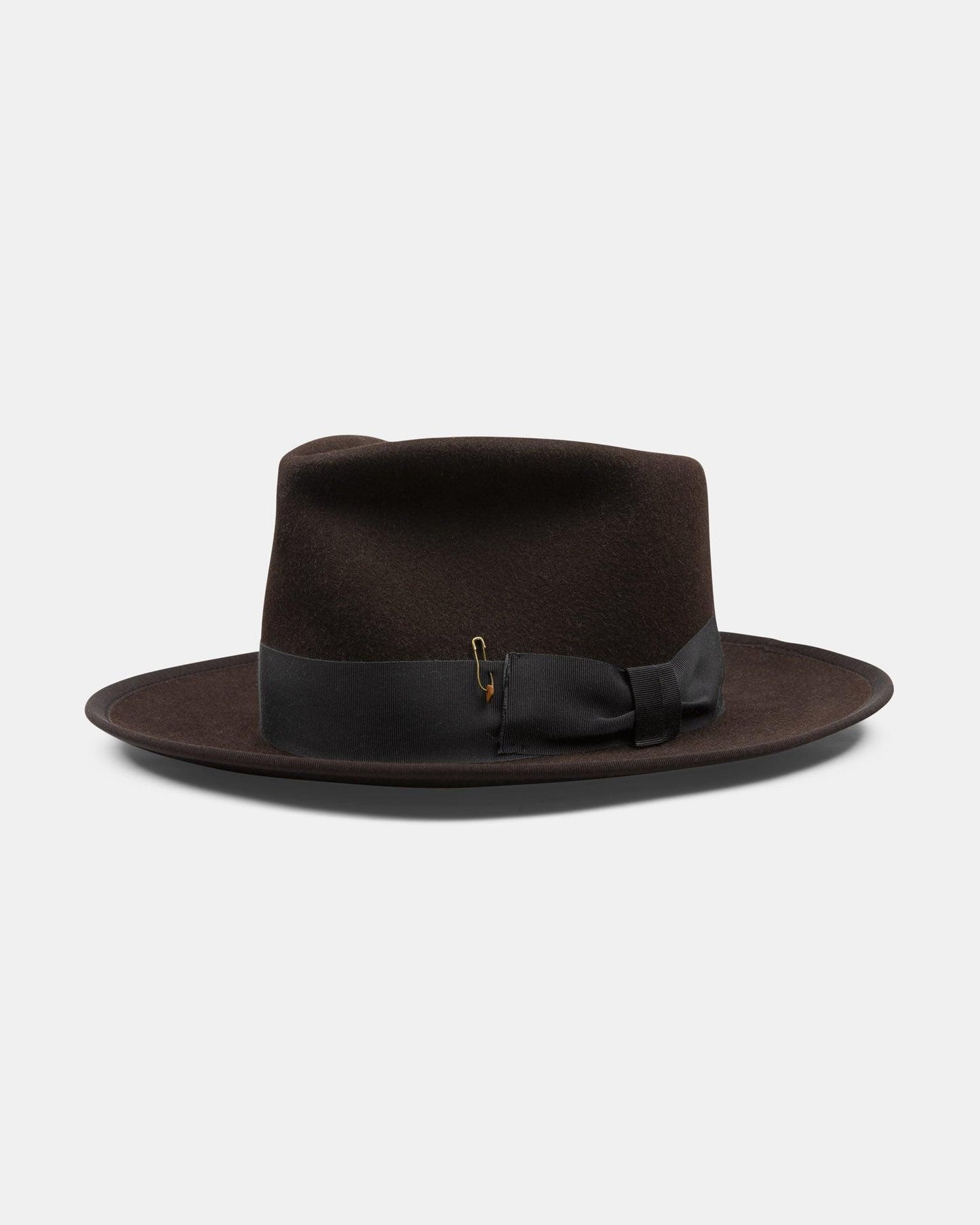 Dark brown felt fedora hat with black ribbon and gold pin on white background