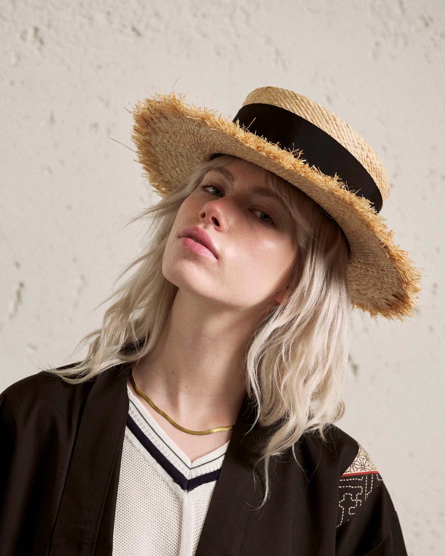 Woman wearing a handmade straw boater hat with frayed brim and black band, fashion portrait