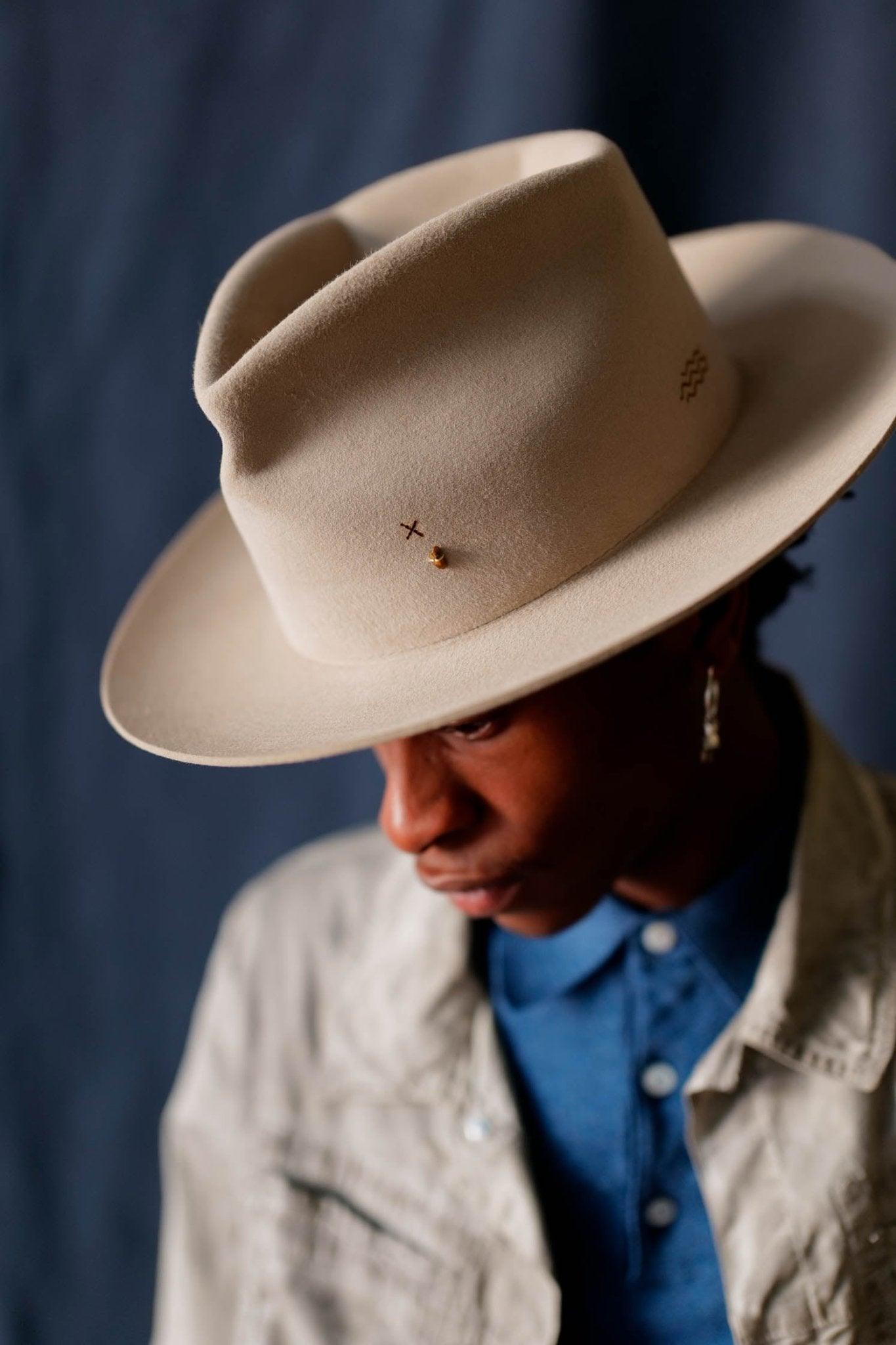 Handmade pastel tan felt hat with unique stitching worn by model in a denim shirt